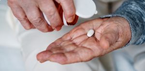 elderly-person-pouring-white-pill-out-of-prescription-bottle