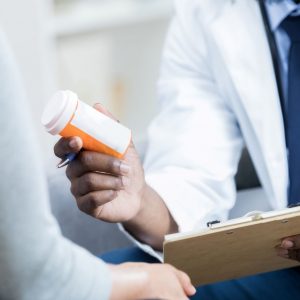 african-american-doctor-handing-female-patient-medication-bottle