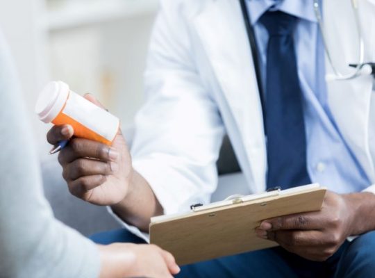 african-american-doctor-handing-female-patient-medication-bottle