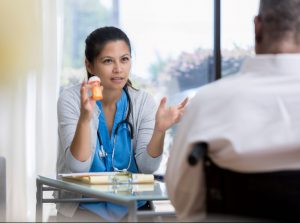 female-doctor-holding-medication-bottle-and-talking-to-a-male-patient