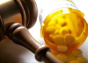 open-prescription-medication-bottle-next-to-a-gavel