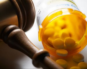 open-prescription-medication-bottle-next-to-a-gavel
