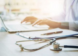 doctor-typing-information-on-laptop-in-hospital-office-focus-on-picture